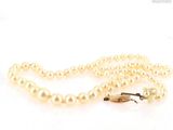a close up of a white pearl necklace with a gold clasp