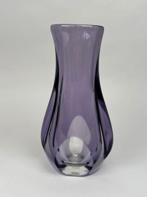un vase en verre violet posé sur une table blanche, sur fond blanc