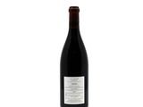 the bottle of red wine is sitting on a white surface