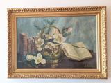 un tableau représentant des fleurs dans un vase et un livre posé sur une table