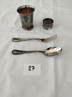 une tasse en argent et deux cuillères posées sur une table