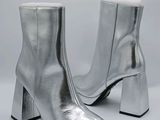 une paire de bottines en cuir argenté sur fond blanc