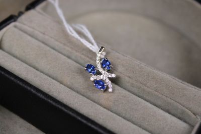 un petit pendentif en forme de losange bleu et blanc, présenté dans un écrin