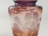 a purple vase with leaves on it on a white surface