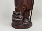 wooden statue of a man with a bucket of fruit and a cane