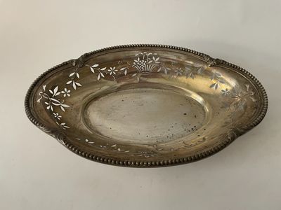 une assiette ancienne en argent, ornée d'un motif floral sur le bord