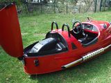 a small red car with a big horn in the grass
