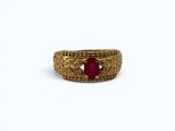 gros plan d'une bague en or avec une pierre en rubis