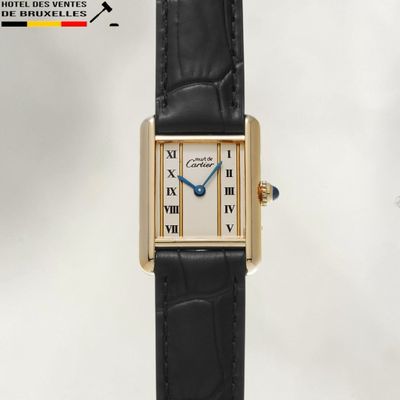 une photo d'une montre avec un boîtier en or et un bracelet en cuir noir