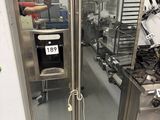un grand réfrigérateur en acier inoxydable dans une cuisine dotée de nombreux plans de travail
