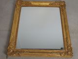 gold framed mirror with a white background on a tile floor