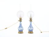 une paire de lampes en porcelaine bleue et blanche suspendues à des chaînes dorées