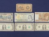 six different canadian bank notes laid out on a blue surface