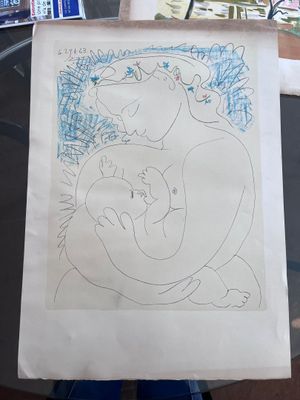 un dessin représentant une femme tenant un bébé dans ses bras, posé sur une table