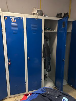 blue lockers in a room with clothes and other items on the floor