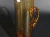 a yellow glass pitcher with a gold handle on a black table