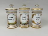 three white and gold canisters with different designs on them