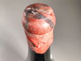 a black bottle with a red substance on the top of it