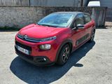 La Citroën rouge est garée sur un parking à côté d'un immeuble