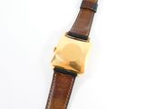 the watch has a gold plated face and a brown leather strap