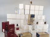 de nombreux flacons et coffrets de parfum posés sur une surface blanche