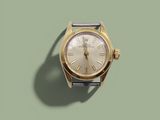 une montre en or avec des chiffres romains sur fond vert