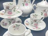 several pieces of porcelain tea set on a table with saucers and cups