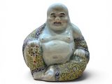 une petite statue représentant un Bouddha souriant, assis sur un coussin