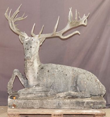 statue d'un cerf assis sur une plate-forme en bois sur laquelle sont posés ses bois