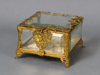 a small glass box with a gold decoration on it
