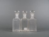 trois bouteilles en verre transparent posées sur une surface grise
