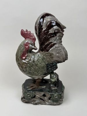 a statue of a rooster on a rock on a white background