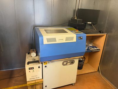 une machine bleue et blanche dans une pièce où se trouve un ordinateur