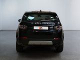 the back end of a black car in a room with a white wall