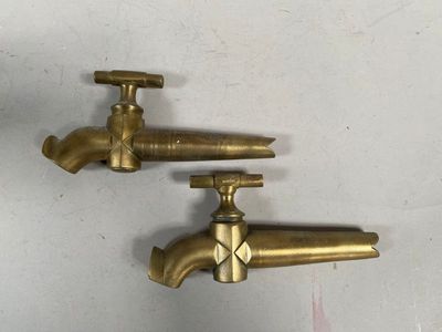two brass faucets on the wall next to each other