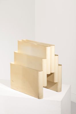 une sculpture en bois posée sur un socle dans une pièce blanche
