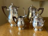 three silver coffee pots sitting on a wooden table