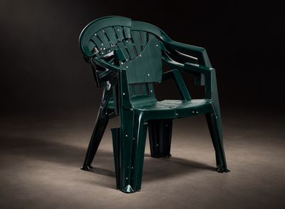 une chaise en plastique verte qui se trouve dans l'obscurité