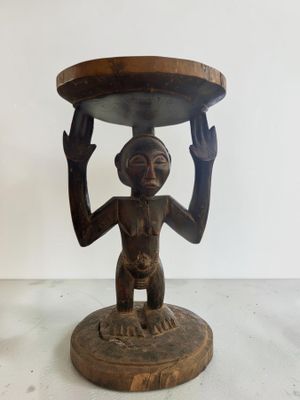 statue en bois représentant un homme tenant un plateau sur la tête