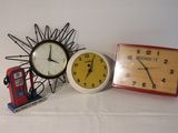 three different clocks and a telephone on a table