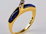 un gros plan d'une bague en or sertie d'une pierre bleue et d'un diamant