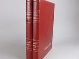 two red books sitting on top of each other on a white surface