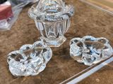 trois objets en verre posés sur une table, avec une boîte à l'arrière-plan