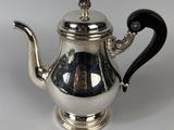 a silver teapot with a black handle on a table