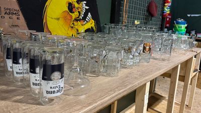 de nombreux verres vides posés sur une table, avec un tableau accroché au mur derrière eux
