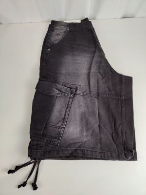un gros plan sur un short en jean noir posé sur une surface blanche