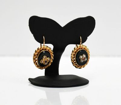a pair of black and gold earrings on a black stand