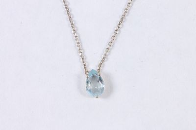 a necklace with a blue topazt stone hangs on a silver chain