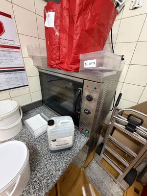 une petite cuisine équipée d'un micro-ondes, d'un grille-pain, de toilettes et d'un sac rouge posé sur le plan de travail