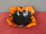 an orange and black flower shaped bowl on a red surface